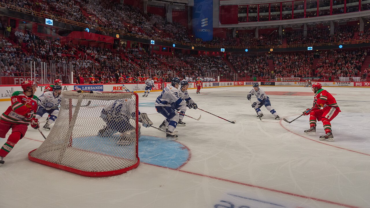 Ishockeymatch i en stor arena med lagen på isen och publik på läktarna