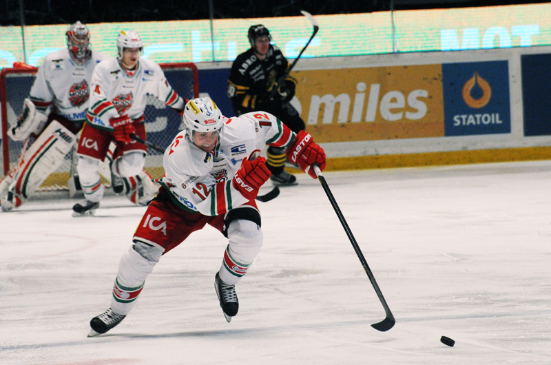 Ishockeyspelare rusar framåt med pucken under en match